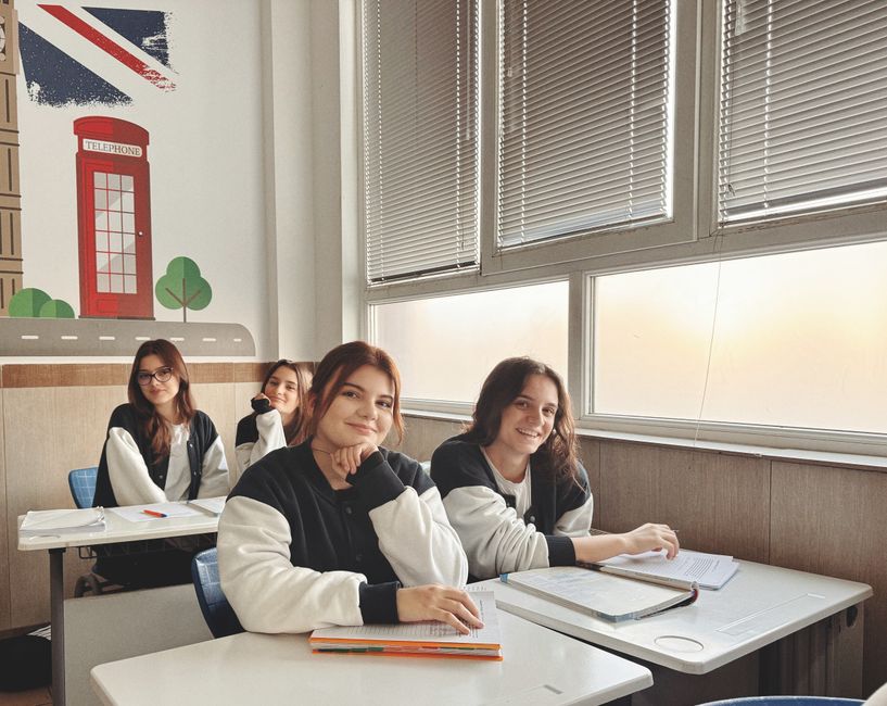 Group of students in a classroom with British decor, studying near a large window.