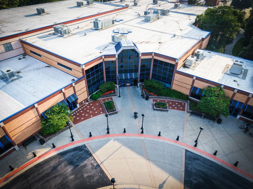 Aerial view of a modern building with glass windows and landscaped entrance.