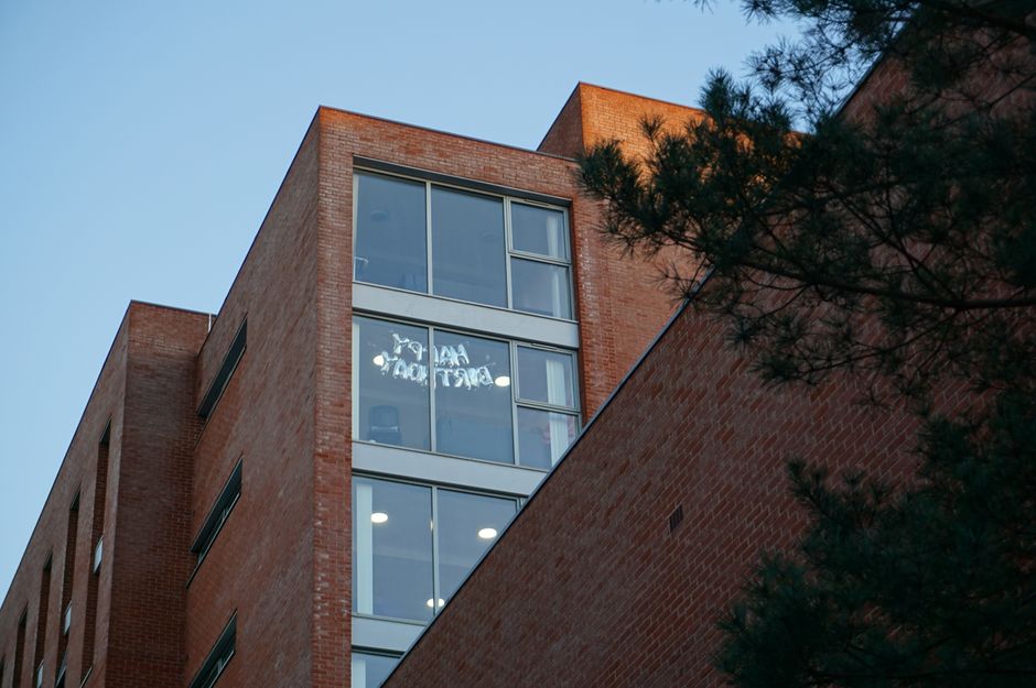 Low-angle view of a modern university building with brick facade and large glass windows.