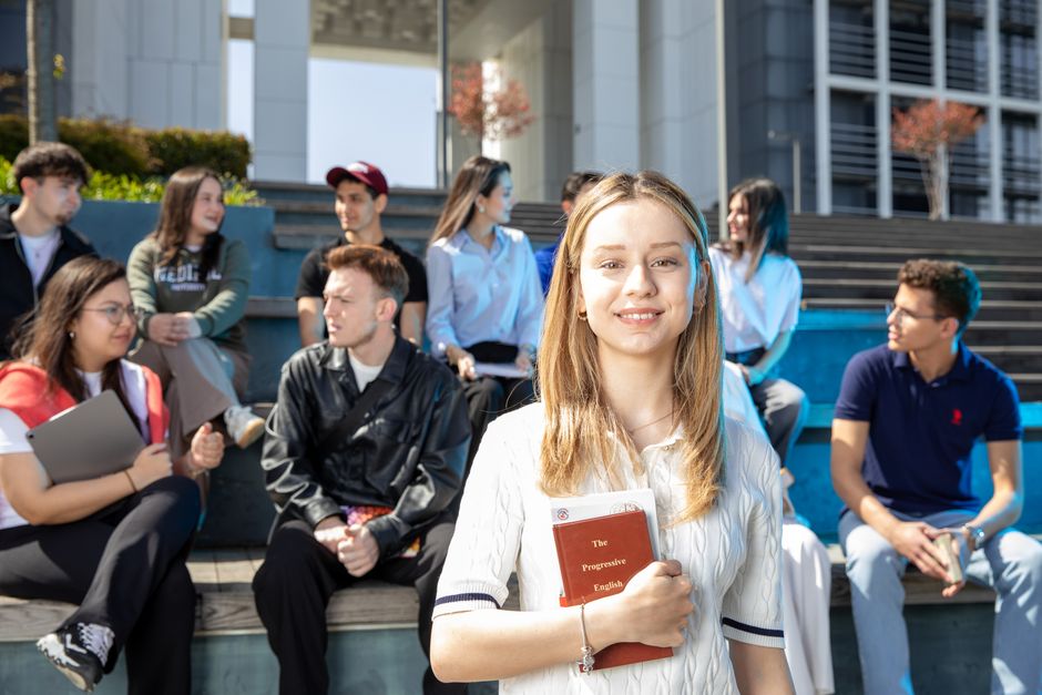 Group of young adults socializing on university steps, discussing and studying together.